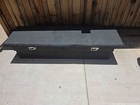 Closed black diamond-plate truck bed tool box front view