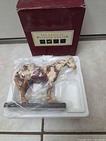 Cowpony figurine wrapped in plastic inside Styrofoam next to maroon box