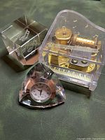 All three items grouped: crystal clock paperweight, acrylic piano music box, engraved cube