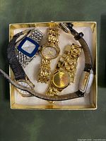 Five watches displayed in box showing bracelets and straps