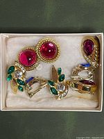All four pairs of gold-tone clip-on earrings arranged in box