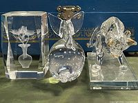 Group shot showing dolphin bubble paperweight, crystal flower block, and glass bull with gold horns