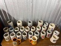 Full collection of approximately 27 stoneware beer steins on tabletop