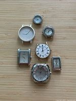 Front view of seven watch heads on wood surface