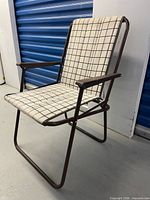 Side view of brown metal folding chair showing frame and fabric pattern