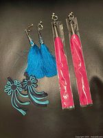 All items: blue tassel earrings, teal/black appliqués, two packaged pink tassels