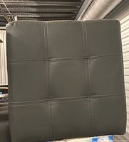 Front view of one grey cube ottoman showing grid stitching