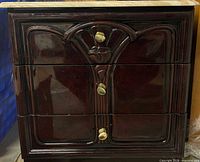 Front view showing three drawers, carved detail, brass knobs