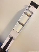 Front of sealed box showing Umbra Flip rack with three visible retractable hooks