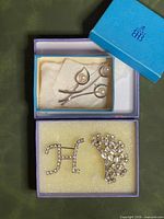 Overview of all three brooches in two boxes