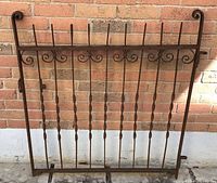 Full view of wrought iron gate against brick wall