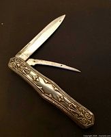 Folding sterling fruit knife open showing straight blade and pick with ornate handle
