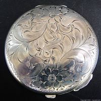 Angled view of engraved sterling silver compact lid