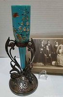 Full view of blue Bristol glass vase in silver-plate stand with cabinet photo in background