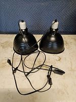 Two black metal heat lamp fixtures side view