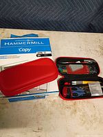 Hammermill copy paper ream with two red stationery cases, one open showing contents