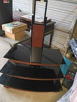 Front view showing three black glass shelves, wood veneer center panel and metal mounting bracket