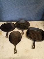 Four cast iron pans laid out, showing shapes and handles