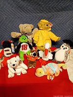 Group shot of all nine plush animals on red cloth