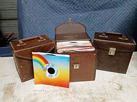 Front view of three brown record cases, one open showing vinyl single