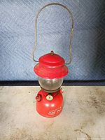 Full view of red Coleman lantern showing handle and globe