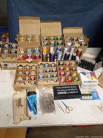 Full lot showing thread cones in boxes, bobbins, stitch eraser, scissors and scale