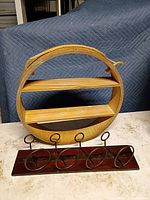 Front view of circular wooden shelf with two tiers and rope hanger, wine rack placed in front