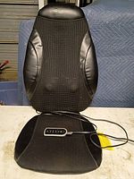 Front view of black Sharper Image back massage pad showing seat and back sections