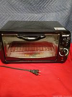 Front view of black Better Chef toaster oven, closed door, plug visible