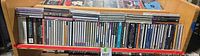 Shelf containing a single row of approximately 70 assorted jewel-case music CDs