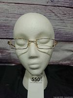 Front view of gold rectangular eyeglasses on mannequin head