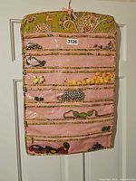 Full view of organizer hanging on door, pockets filled with jewelry