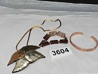 Overview of all three jewelry pieces: pendant necklace, link bracelet, cuff bracelet