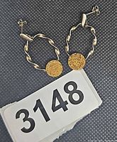 pair of sterling silver twisted oval earrings with gold druzy stones alongside lot number