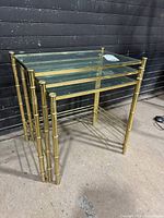 Three brass faux-bamboo nesting tables stacked together showing overall design and glass tops