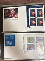 Both first day covers in protective sleeve, showing cachets and stamp blocks