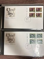 Overall view of two First Day Covers in plastic sleeves showing both stamp blocks and cachets