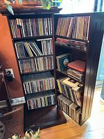Cabinet open showing interior CD shelves filled with CDs