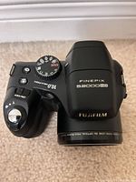 Top view showing Fujifilm FinePix S2000HD model name mode dial and lens barrel
