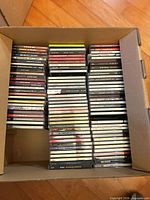Box filled with stacked jewel-case CDs showing quantity and general condition