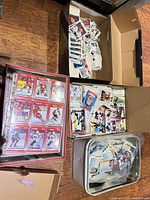 Overview of three open boxes and tin containing large volume of hockey cards, some sleeved in binder pages