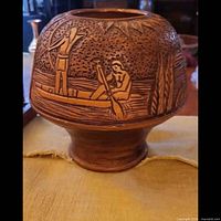 Front view showing canoe and villagers carving on terracotta planter