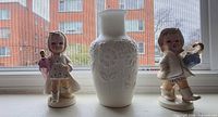 Front view of both figurines flanking the milk glass vase