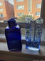 Front view of cobalt bottle and crackle art glass vase side by side