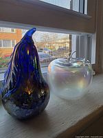 Iridescent glass pear and opalescent glass apple on windowsill