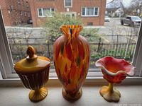Group shot of vase, compote with lid, and ruffled bowl on windowsill