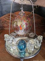 Full view of ornament on stand with mirrored tray and glass figurines