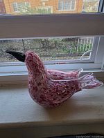 Side view showing mottled pink body, clear glass exterior and black beak