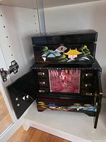 Overall view of open lacquered jewelry box showing drawers, door, and painted exterior