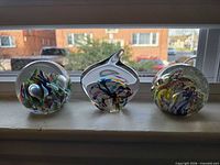 Front view of all three glass paperweights on windowsill